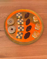 Sip & Paint: Paper Lanterns-themed cookies arranged on an orange plate, showcasing various shapes and designs.
