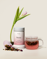 Image of the Complete Functional Tea Set featuring the Beauty tea blend, a glass mug, and a flower.