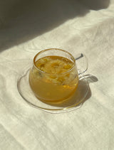 A glass of Wild Chrysanthemum tea, showcasing its delicate floral petals and soothing golden hue.