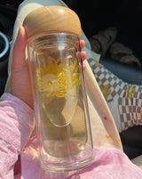 Paradise Double Wall Glass Bottle with floral design held in hand, showcasing sustainable hydration.