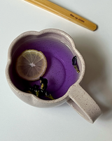 Butterfly Pea tea with lemon slice in a unique cup, showcasing vibrant blue-violet color and dried flowers.