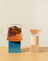 Gold rim glass cups (2) next to a Bloom glass teapot with herbal tea, showcasing elegant design and color contrast.