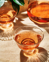 Gold rim glass cups (2) filled with tea, beautifully reflecting light on a table.