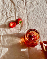 Image of glass cups & saucers (2) with a tea mixture and fresh strawberries, highlighting elegant dining.
