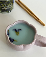 Cup of Butterfly Pea tea with dried flowers, showcasing its blue-violet color and unique presentation.
