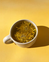 Floral Collection - Variety Box featuring blooming chrysanthemum tea in a cup on a vibrant yellow background.