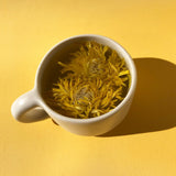 Floral Collection - Variety Box featuring blooming chrysanthemum tea in a cup on a vibrant yellow background.