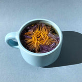 Floral Collection - Variety Box featuring blooming flower tea in a light blue cup on a textured background.