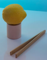 Handmade Bamboo Tong placed beside a lemon on a pink stand, perfect for flower sipping rituals.
