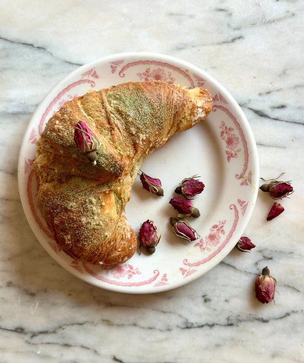 Matcha Rose Croissants on a decorative plate surrounded by dried rose buds.