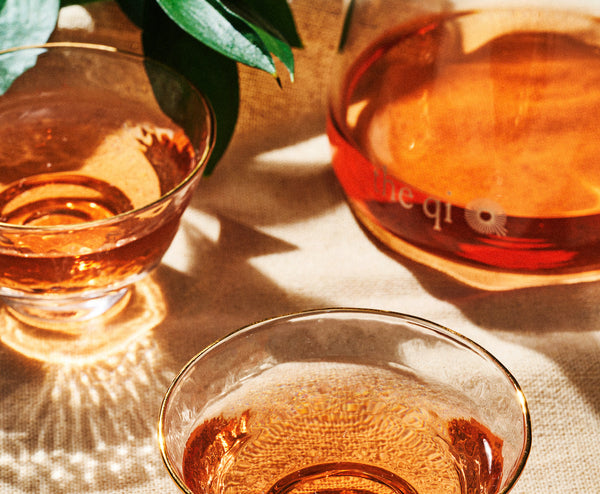 A Tea Ritual + Rose Hot Toddy For Holiday Stress with two glasses and a pitcher of rose tea on a table.