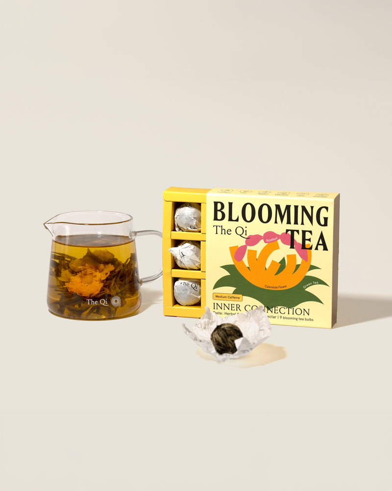 Inner Connection Blooming Tea box with blooming tea truffles and brewed tea in a glass pitcher.