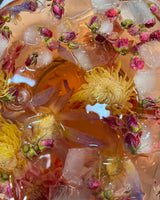 Shark Tank Special! Blooming flower tea with ice cubes in colorful brew, showcasing vibrant floral ingredients.