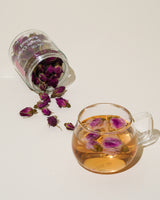 Shark Tank Special! Floral tea in glass cup with blooming rose petals spilling from jar.