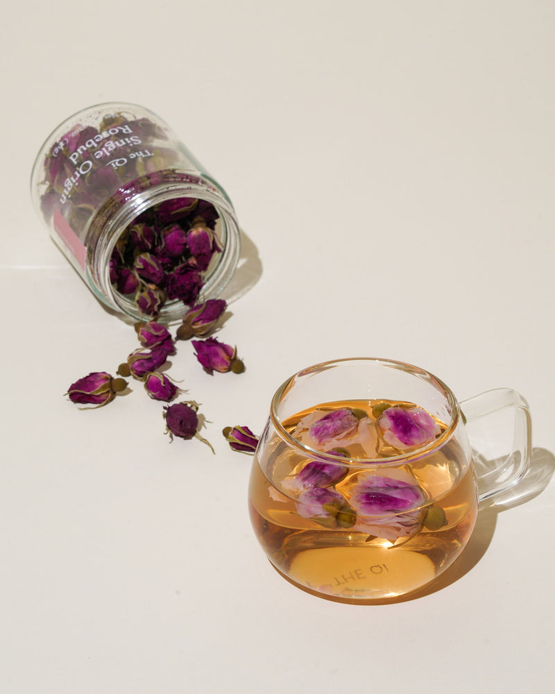 Shark Tank Special! Floral tea in glass cup with blooming rose petals spilling from jar.